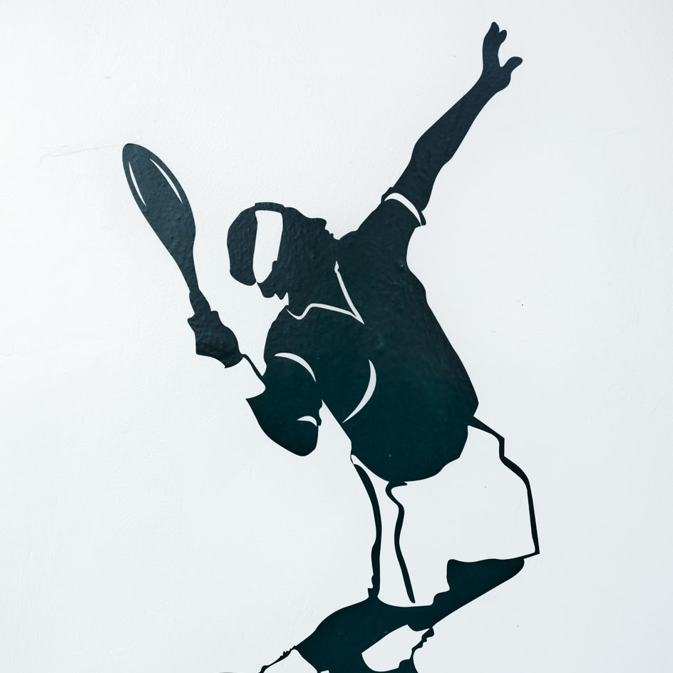 Silhouette eines Tennisspielers, der einen Aufschlag ausf&uuml;hrt, mit erhobenem Schl&auml;ger und Ball in der Luft.