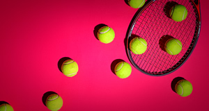 Tennisb&auml;lle und ein Tennisschl&auml;ger auf einem pinken Hintergrund.