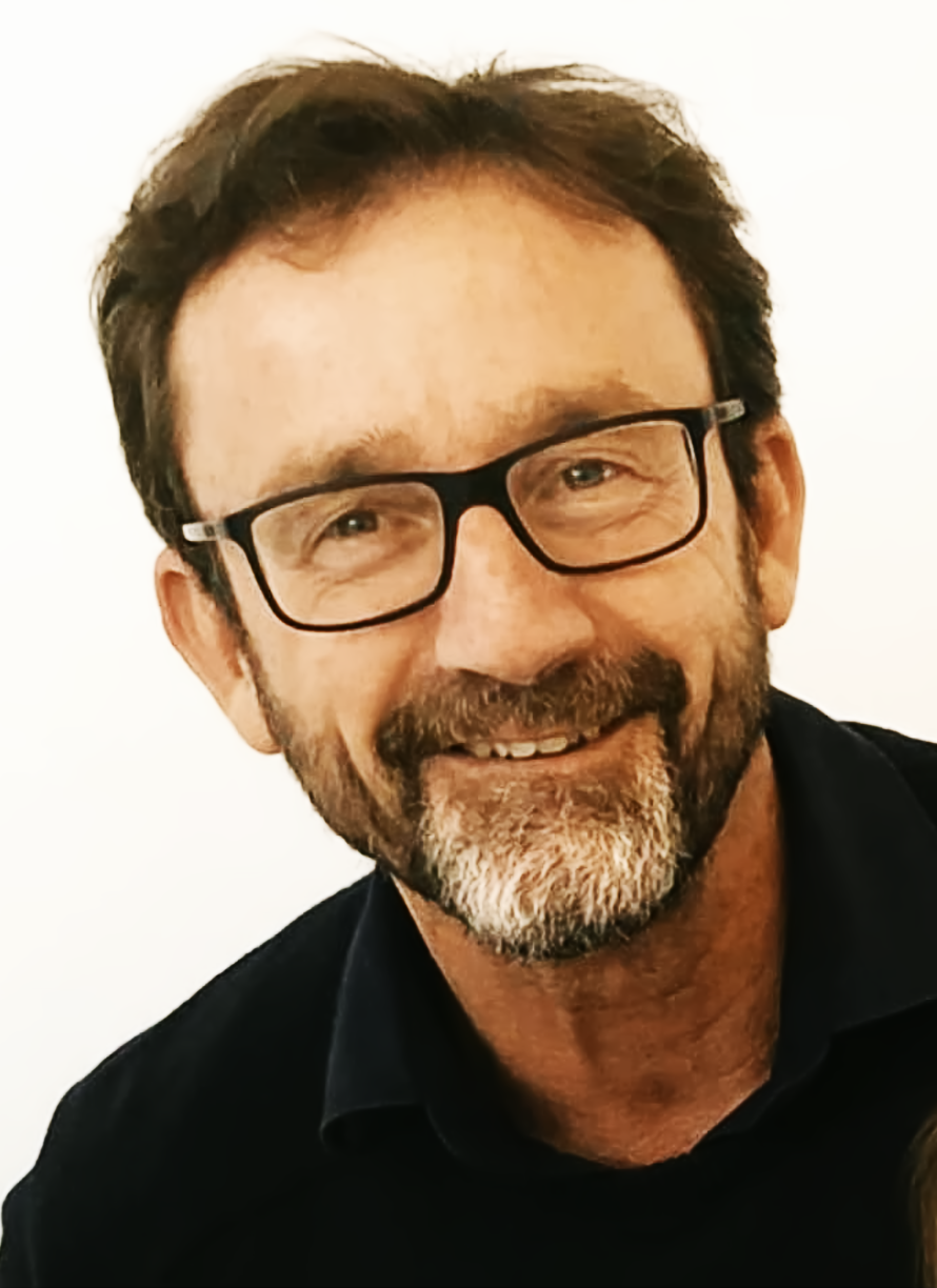 Mann mit Brille und Bart l&auml;chelt in die Kamera vor einem wei&szlig;en Hintergrund.