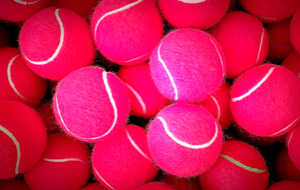 Mehrere pinke Tennisb&auml;lle mit wei&szlig;en Linien.