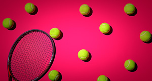 Ein Tennisschl&auml;ger und mehrere gelbe Tennisb&auml;lle auf einem pinken Hintergrund.